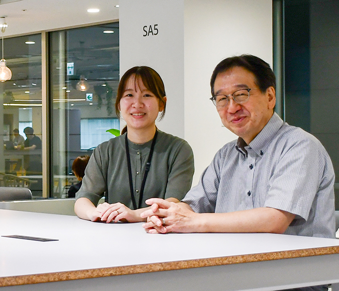 NECのオフィスにて並んで座るNEC GX事業開発統括部の廣光徹と甲斐 綾乃の様子