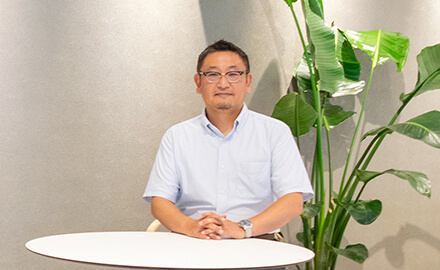 NEC本社オフィスで座っているNEC エンタープライズコンサルティング統括部PLMグループ ディレクター 杢田竜太