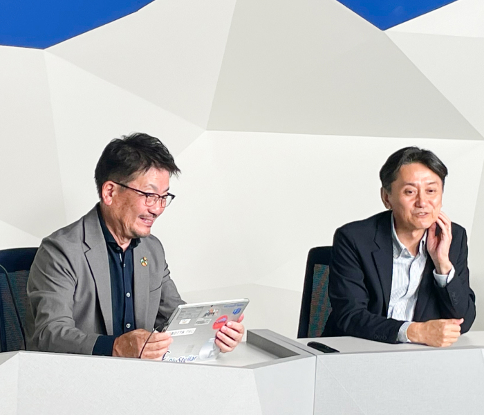 セミナー会場でリラックスした雰囲気で談笑する株式会社アドヴィックス 半田工場 技術員室ものつくり支援グループ グループリーダー　乾 善人氏とNEC スマートインダストリー統括部　シニアビジネスプランナー　北野 芳直